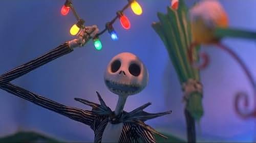 Jack Skellington is standing under Christmas lights holding something in his hand 