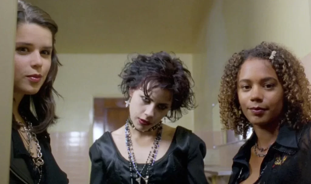 3 high school girls are standing in the door way of a bathroom stall 